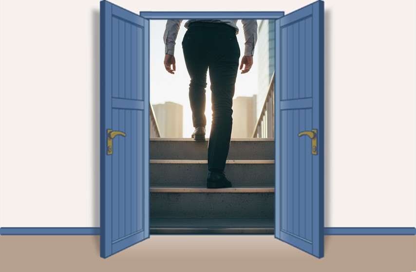 青い両開きの扉の向こうで、朝の光の中、ビルの階段を上っていく男性の足元を後ろから捉えたクローズアップ